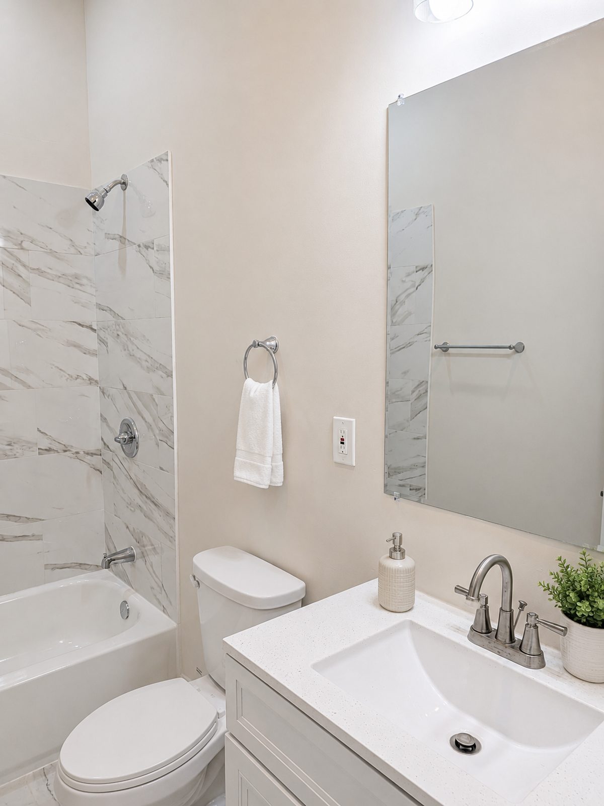 Updated bathroom with marble-look tiled shower, quartz vanity, and brushed nickel fixtures